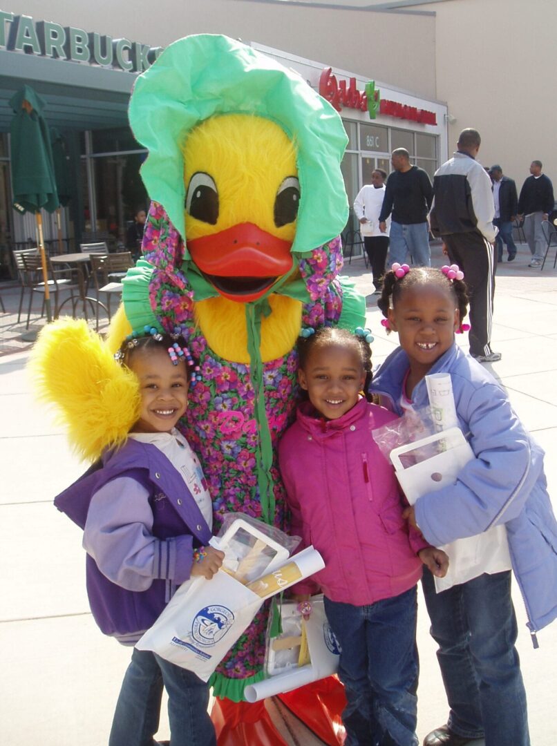 daisy duck mascot posing with three girls