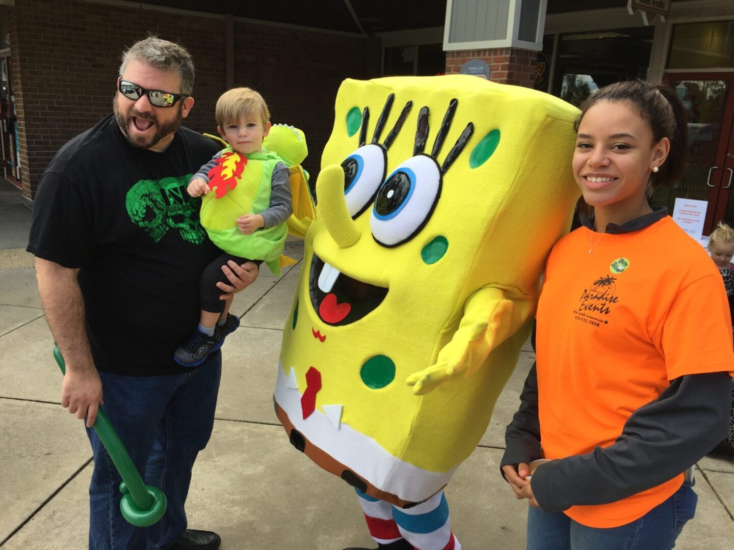 two people and a toddler posing with a spongebob squarepants mascot
