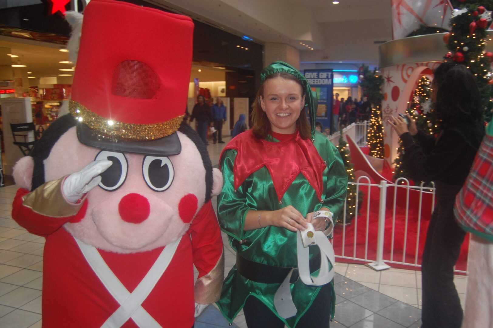 a toy soldier mascot with a woman dressed as an elf